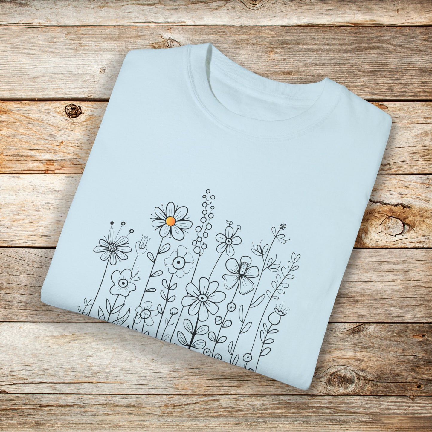 Chambray shirt with a minimalist black line art design featuring a variety of whimsical flowers and stems. One flower stands out with a small pop of yellow at its center, adding a subtle touch of color to the elegant floral arrangement.